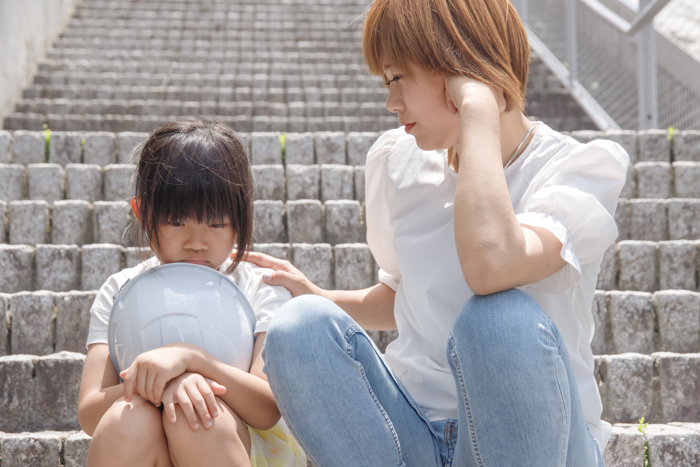 ヘルメットを嫌がる小学生の子供と困ったママ